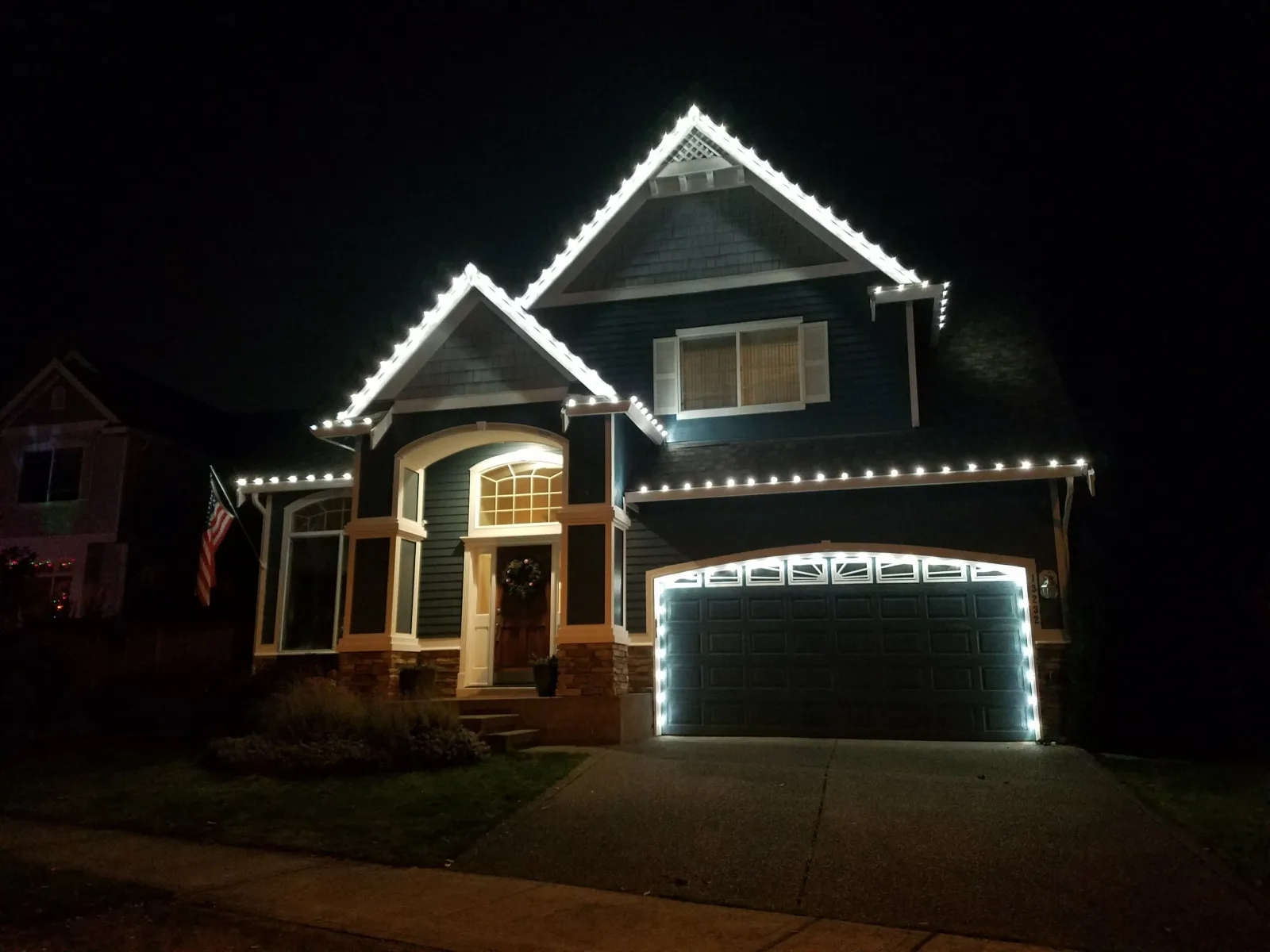 Warm white holiday light strand clipped in even spacing along the front gutter line of a house at dusk