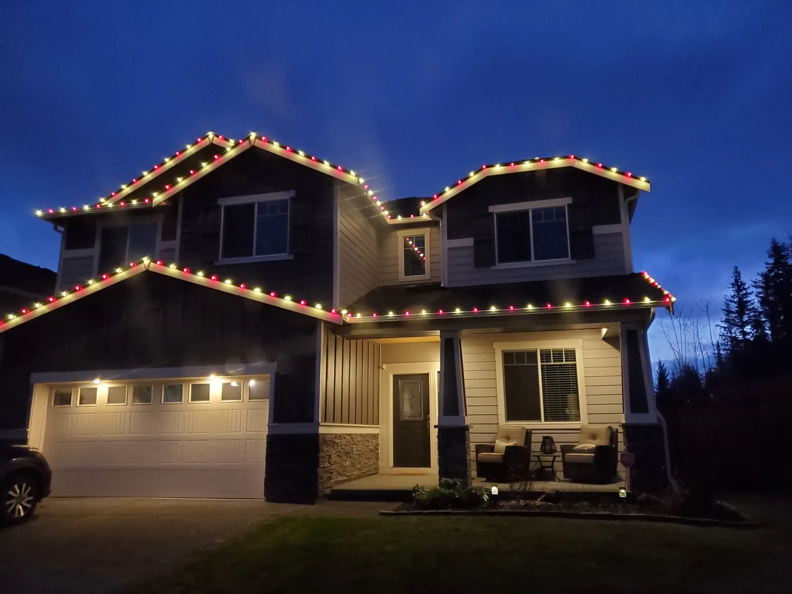 Two story home at dusk with an even run of warm white lights following the roofline and gutter edge