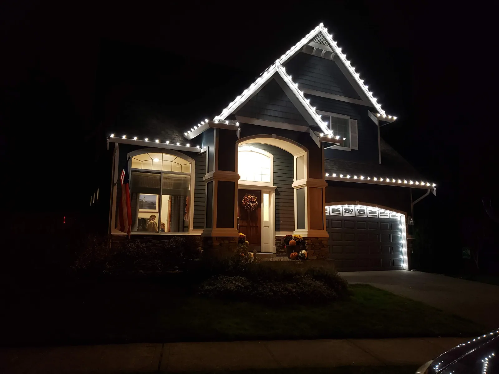 Craftsman home lit with white holiday lights following the gables and porch roof