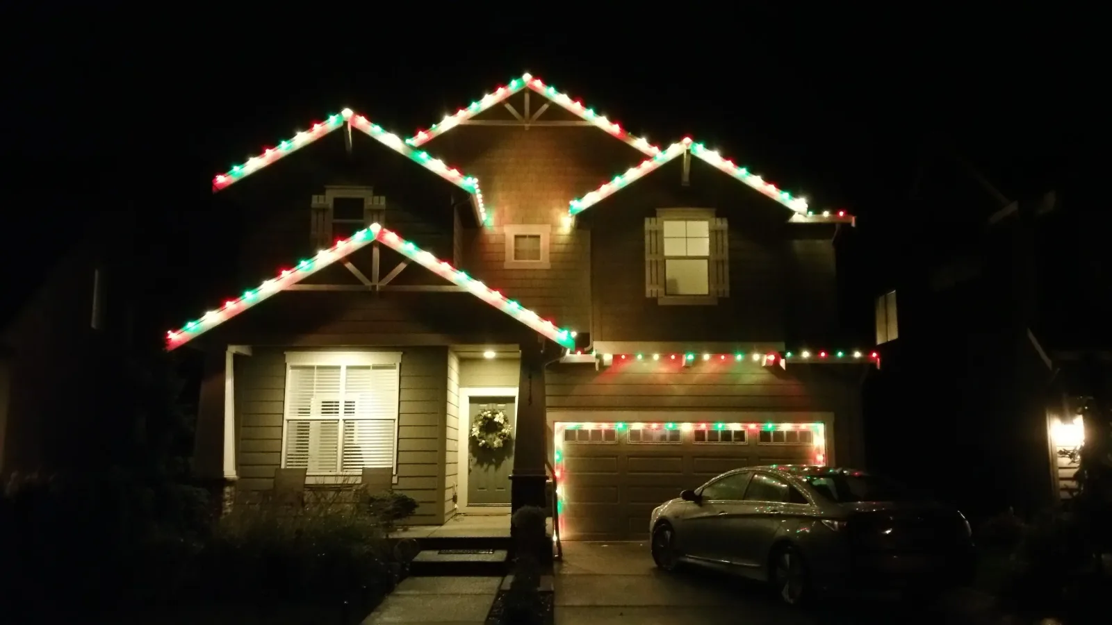 Two story home outlined in red and green holiday lights along the rooflines