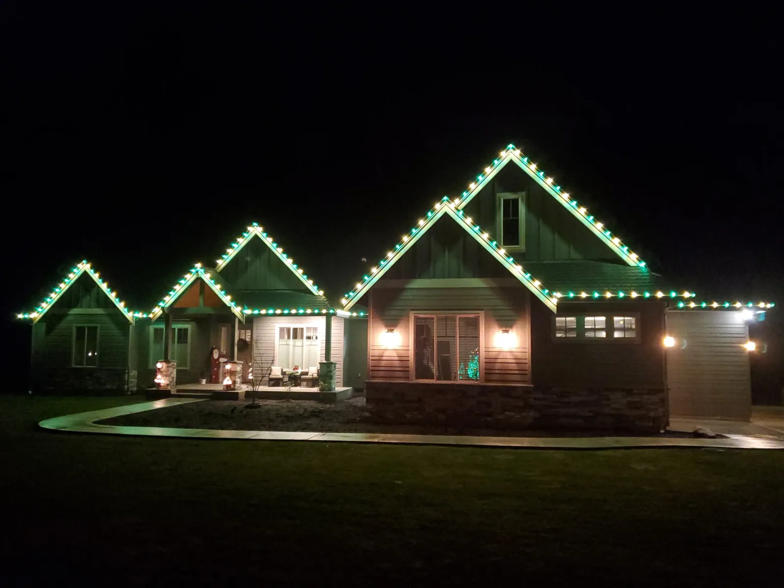 Single story home traced with holiday lights along the roof peaks at night